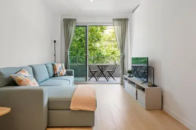 a living room with a blue couch and a balcony at Monthly 32 Nights 1BR Pools Parking in Barcelona