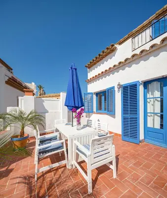 a patio with a table and a blue umbrella at Blue Home in Sitges