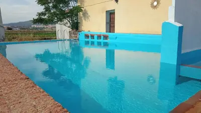 a blue swimming pool in front of a building at TURISME RURAL HORTA del PI in Cabrera de Mar