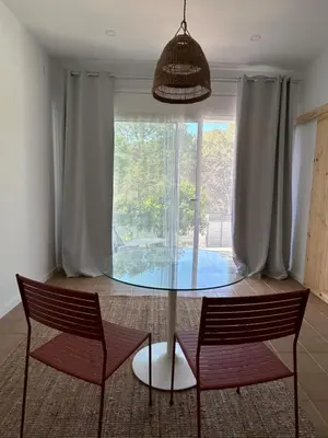 a glass table and two chairs in a room with a window at Son Roca Ribes Guest House in Sant Pere de Ribes