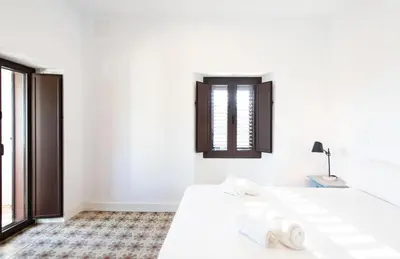 two beds in a white room with two windows at Unique 16th-Century Masia, Pool & Private Events in Barcelona