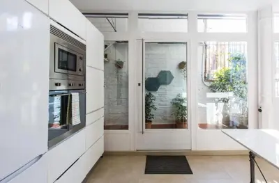 a kitchen with white walls and a sliding glass door at Provenza Flat in Barcelona