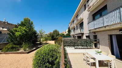 a patio with a table and chairs next to a building at Bajos con jardín in Terrassa