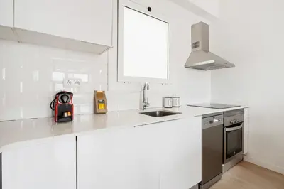 a kitchen with white cabinets and a sink and a window at Flateli Calàbria in Barcelona