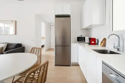 a kitchen with a stainless steel refrigerator and a table at Flateli Calàbria in Barcelona