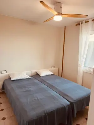 a bedroom with a blue bed with a ceiling fan at Apartamento en 1ª línea con vistas al mar cerca de Barcelona in Pineda de Mar