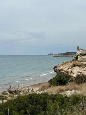 a beach with people on the sand and the ocean at Quiet Apartment in Sitges Center Steps from Beach in Sitges