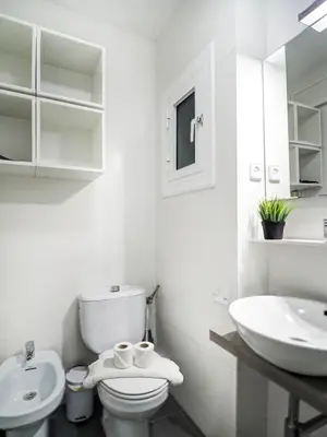 a white bathroom with a toilet and a sink at Warm Sands Apartment by Hello Homes Sitges in Sitges