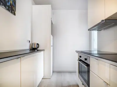 a kitchen with white cabinets and black counter tops at Warm Sands Apartment by Hello Homes Sitges in Sitges