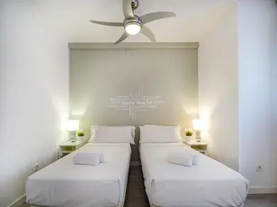 two beds in a room with a ceiling fan at Warm Sands Apartment by Hello Homes Sitges in Sitges