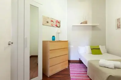 a small room with a bed and a dresser in it at Urgell in Barcelona