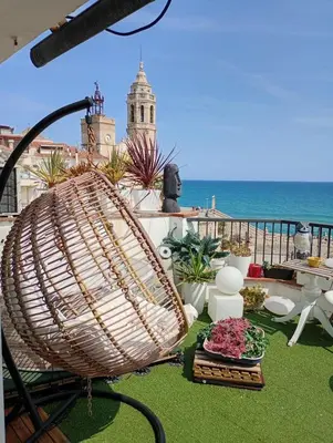 a large rattan chair on a balcony with the ocean at Frente al mar con Terraza - Sitges in Sitges