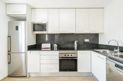 a white kitchen with white cabinets and a refrigerator at 4182 - AB Poble Sec - Plaza España X in Barcelona
