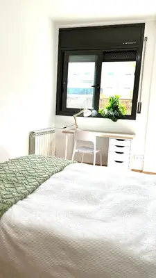a bedroom with a bed and a table and a window at Apartamento independiente con jardín in Terrassa