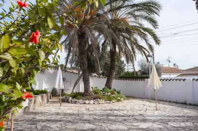 a patio with two umbrellas and a palm tree at Ibiza style villa with swimming pool near Sitges in Cunit