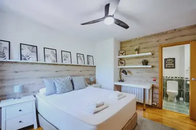 a bedroom with a large white bed and a bathroom at 3 bedroom Huge apartament near the beach in Sant Adria de Besos