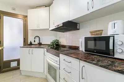 a kitchen with white cabinets and a microwave at Toledo House Self Checkin in Hospitalet de Llobregat