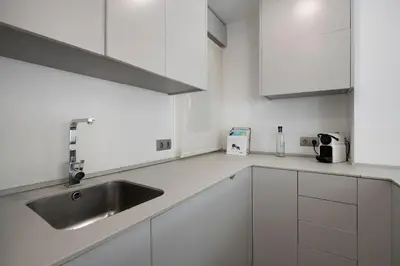 a white kitchen with a sink and white cabinets at Namasté by Seaside Homes in Castelldefels