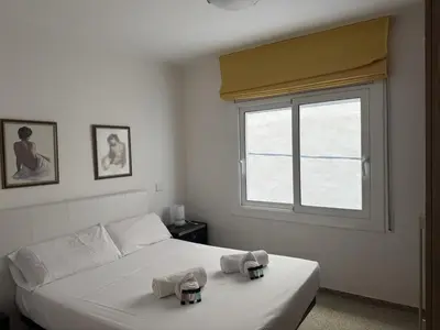 a white bedroom with a bed with towels on it at Apartamento Pineda de Mar en Primera Línea in Pineda de Mar