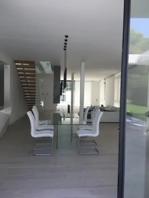 a dining room with a glass table and white chairs at Casa de lujo en Gavá mar in Gavà