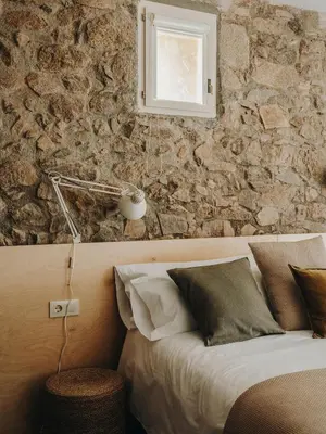 a bedroom with a bed and a stone wall at Paratgea in Llinars del Vallès