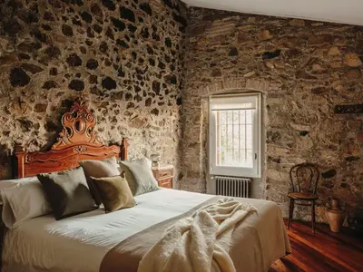 a bedroom with a large bed in a stone wall at Paratgea in Llinars del Vallès