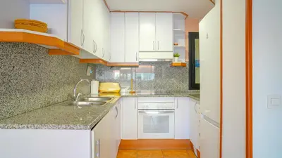 a kitchen with white cabinets and a sink at Vivalidays Margarita - Pineda de Mar in Pineda de Mar