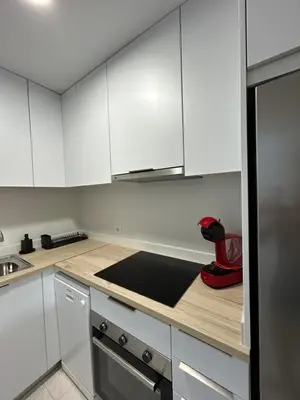 a kitchen with white cabinets and a black counter top at Apartamento con Terraza,Piscina,Playa y Aire acondicionado in Pineda de Mar