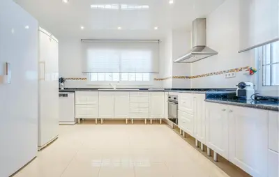 a white kitchen with white cabinets and blue counter tops at Lovely Home In Segur De Calafell in Segur de Calafell