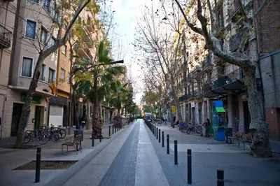 an empty city street with trees and benches and buildings at Two bedrooms bright apartment center Barcelona in Barcelona