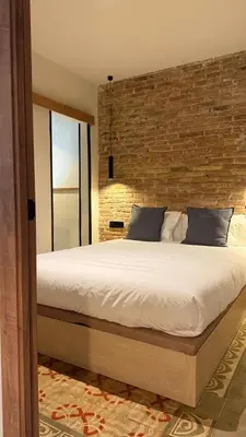 a bedroom with a large bed with a brick wall at Two bedrooms bright apartment center Barcelona in Barcelona