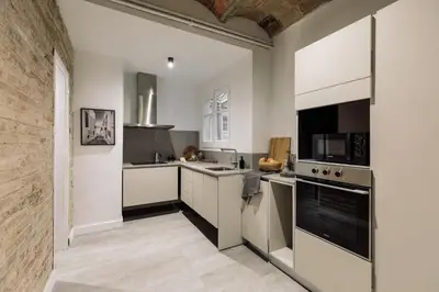 a white bedroom with a large bed and a chair at Morell - 3 bedroom and office in Eixample Esquerra in Barcelona