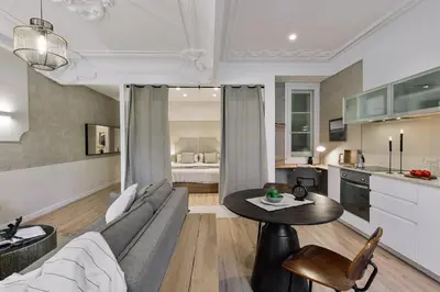 a living room with a couch and a kitchen at Baia - Studio and balcony in Eixample Esquerra in Barcelona