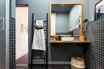 a black tiled bathroom with a sink and a mirror at Depok - 2 bedrooms and balcony in Eixample Dreta in Barcelona
