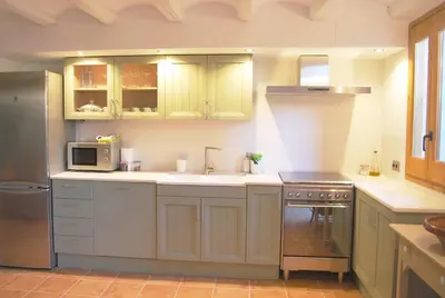 a kitchen with a sink and a stove and a microwave at Casa rural Cal Farriol in Mediona
