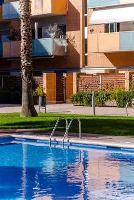 a swimming pool in front of a building with a palm tree at Glorious Sunny penthouse near the beach in Barcelona