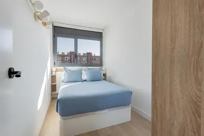 a small bedroom with a bed and a window at Quiet modern 2 bed apartment with Balcony, Pool and Free Parking in Barcelona