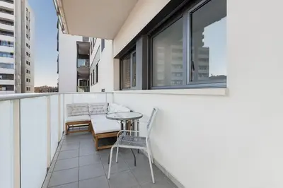 a balcony with a table and chairs on a building at Quiet modern 2 bed apartment with Balcony, Pool and Free Parking in Barcelona