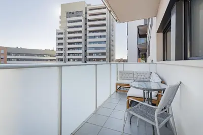 a balcony with a table and chairs and a building at Quiet modern 2 bed apartment with Balcony, Pool and Free Parking in Barcelona