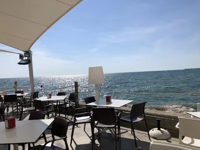 a restaurant with tables and chairs and the ocean at Holiday near Sitges with private terrace in Vilanova i la Geltrú