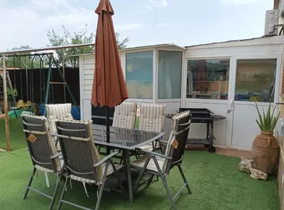 a table and chairs and an umbrella on a lawn at Brad House in Can Trabal