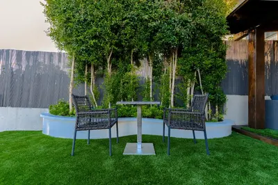 three chairs and a table in a yard with plants at Beachy House - Casa en Montgat, Barcelona in Montgat
