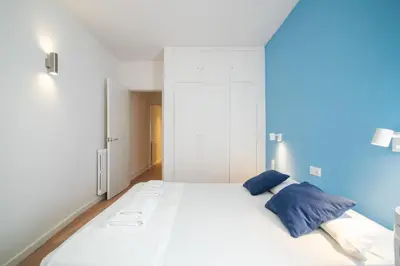 a bedroom with a large white bed with blue pillows at Sunset Beachfront in Sitges in Sitges