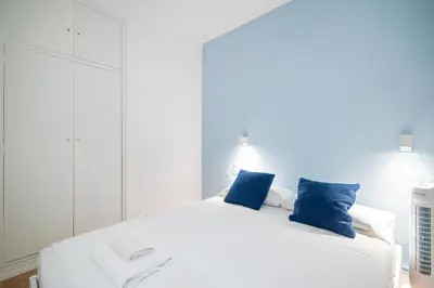 a bedroom with a white bed with blue pillows at Sunset Beachfront in Sitges in Sitges
