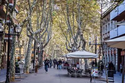 a street with people walking down a street with trees at Sweett - Loft Villa Olimpica Beach in Barcelona
