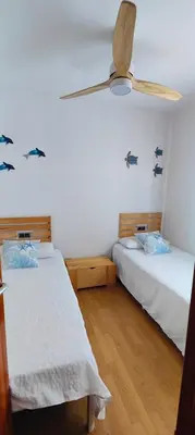 two beds in a room with a ceiling fan at Vilanova Beach Stay in Vilanova i la Geltrú