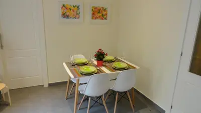 a small dining room table with white chairs and a table with food at Apartamento zona playa de San Sebastian in Sitges