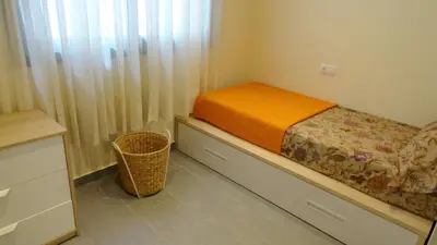 a small bedroom with a bed and a basket at Apartamento zona playa de San Sebastian in Sitges