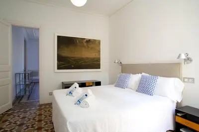 a bedroom with a large white bed with blue pillows at BarcelonaForRent The Claris Suites II in Barcelona