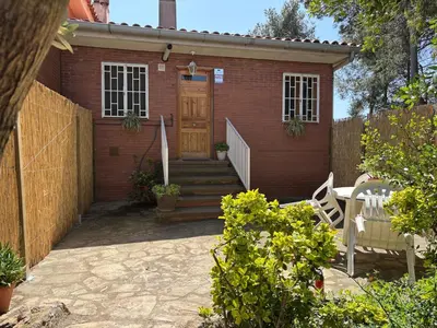 a small brick house with a wooden door and stairs at Can Bosquet - Casa de invitados adosada a casa familiar in Corbera de Llobregat